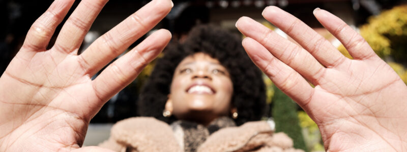 Close-up of palm of hands of young woman in the street. Only the hands are in focus, her face is blurry. It is a cold winter day and she is wearing a thick coat and scarf